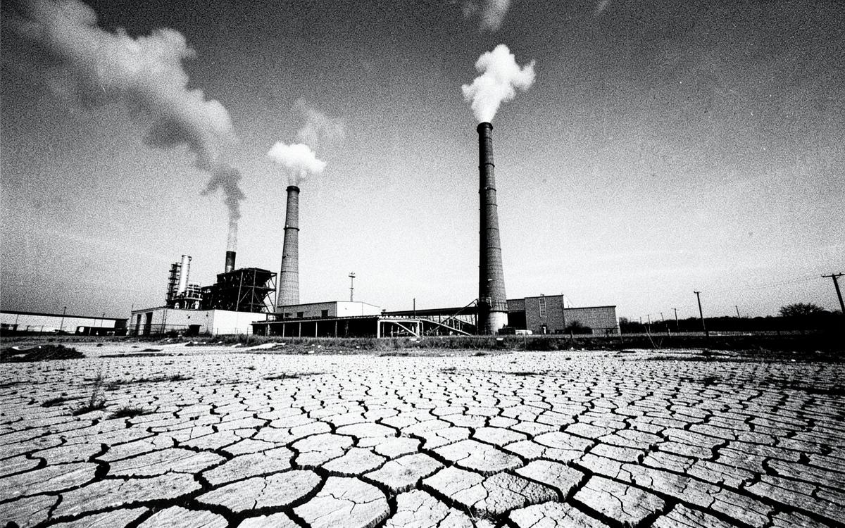Industrial smokestacks above cracked, dry ground