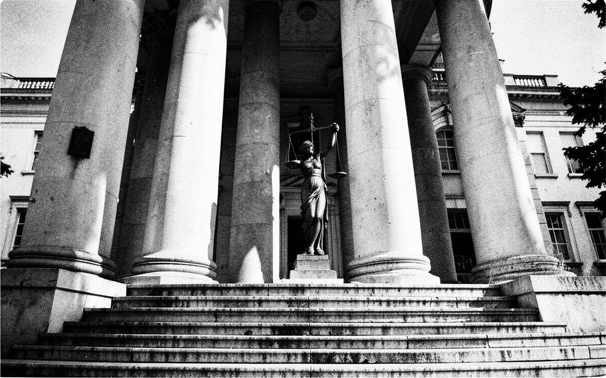 Courthouse steps with columns and a statue of justice