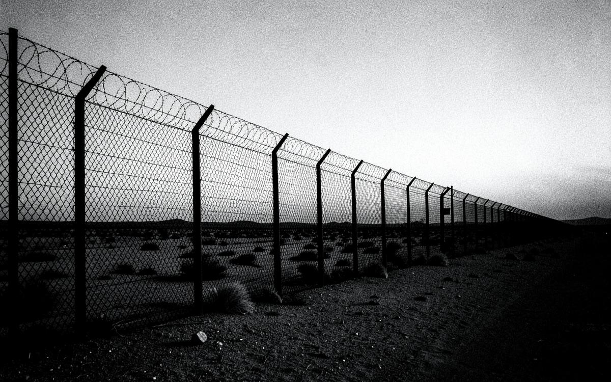 A tall border fence stretching across open desert