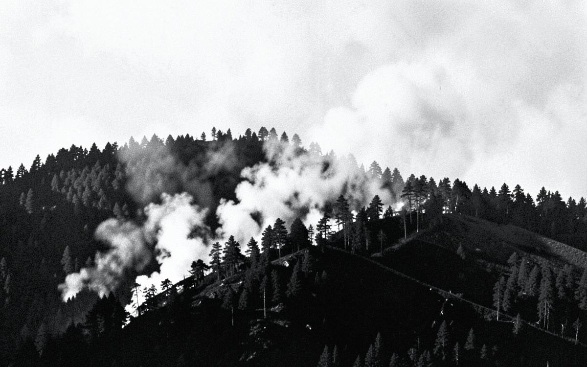 A wildfire burning along a forested ridge